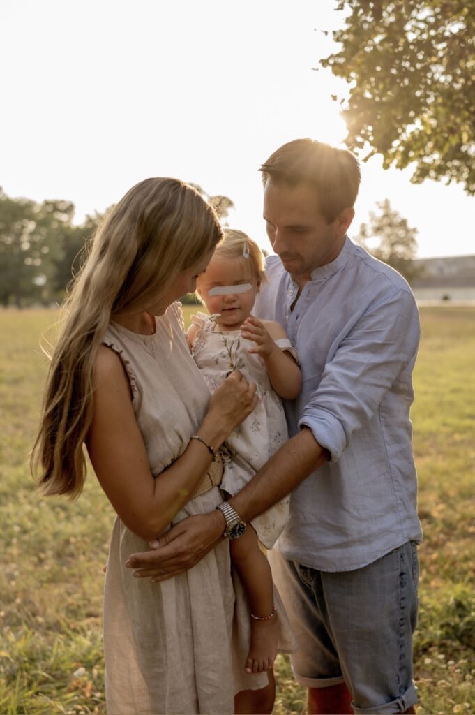 familienfotografin-niederoesterreich-mutter-tochter-vater-sonnenuntergang-blume-riechen