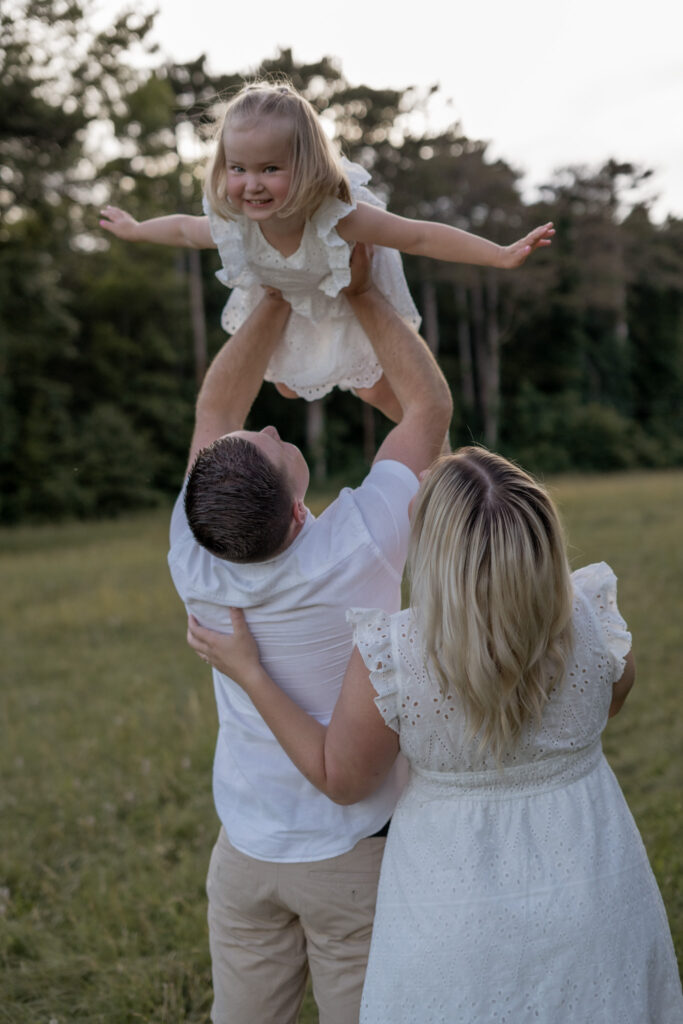familienfotos-niederoesterreich-vater-mutter-kind-auf-wiese-kind-fliegt