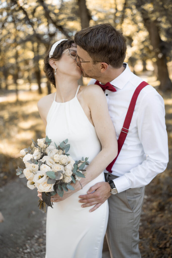 hochzeitsftografin-niederoesterreich-braeutigam-steht-hinter-braut-kuessen-sich