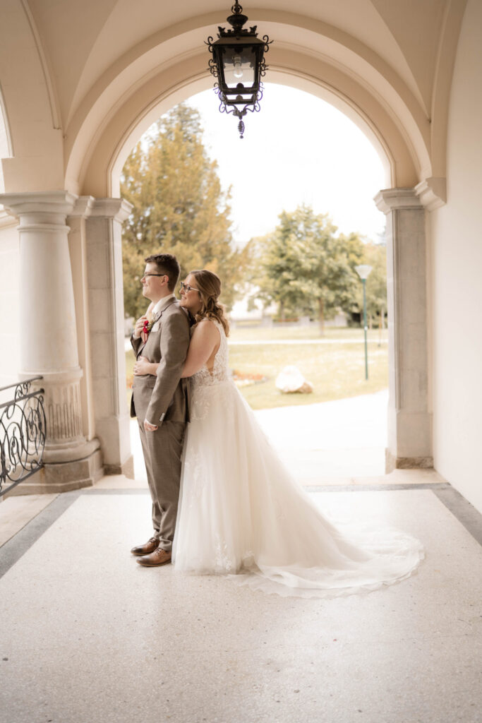 braut-steht-hinter-braeutigam-in-rundbogen-hochzeitsfotografin-niederoesterreich