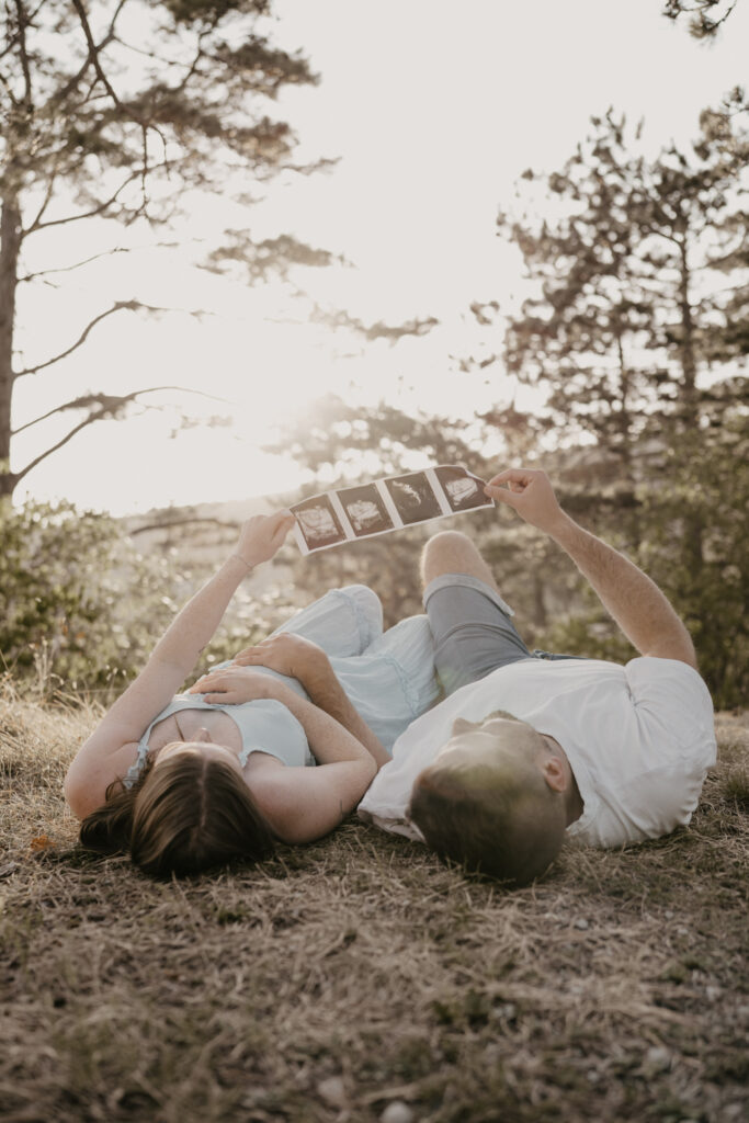 paar-sieht-sich-fotostreifen-an-liegend-im-sonnenlicht-Babybauch-shooting